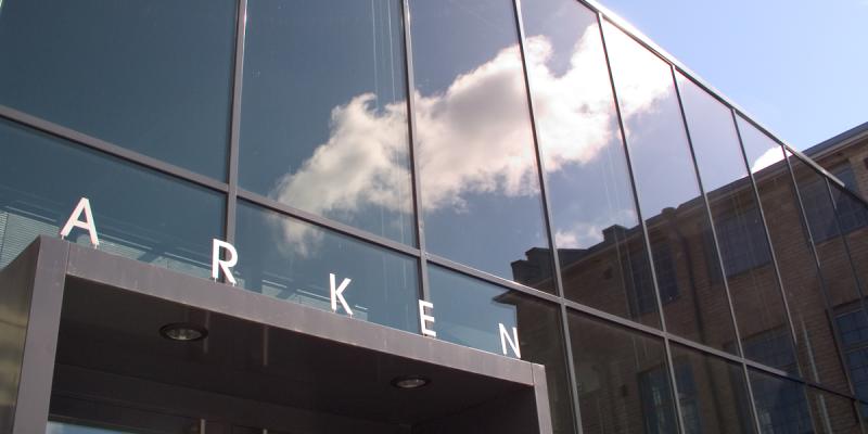 The Arken building in Turku, with a cloud against a blue skye reflected in its glass front.lected in its glass Akademin rakennus Arken, jonka lasisessa julkisivussa heijastuu pilvi sinisellä taivaalla.