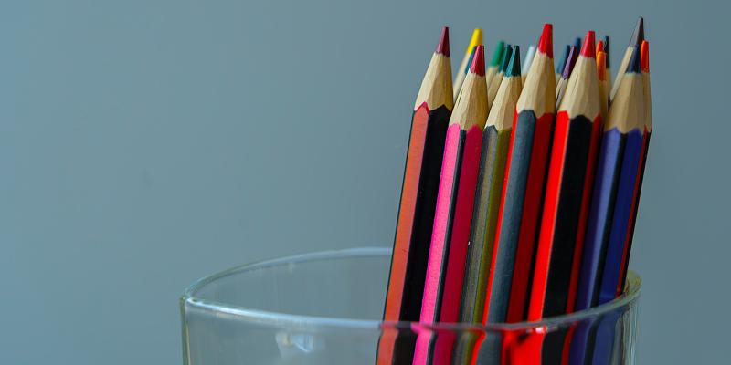 Illustration: Coloured pencils of different colours in a glass. 